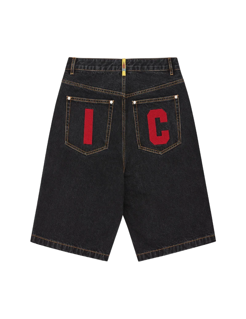 Black denim shorts with red letters on the back pockets against a white background