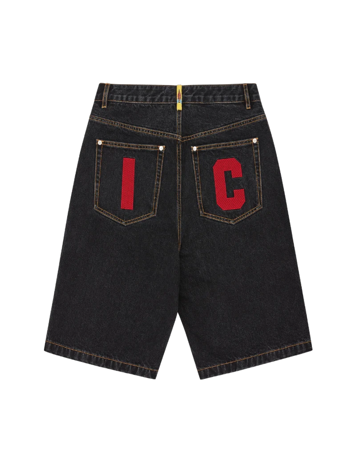 Black denim shorts with red letters on the back pockets against a white background