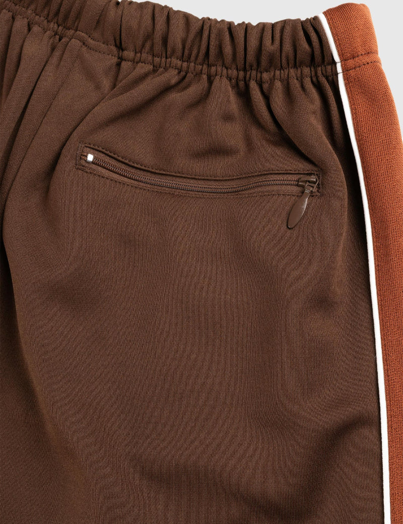 Brown sweatpants with a zipper pocket and white stripe on a light gray background